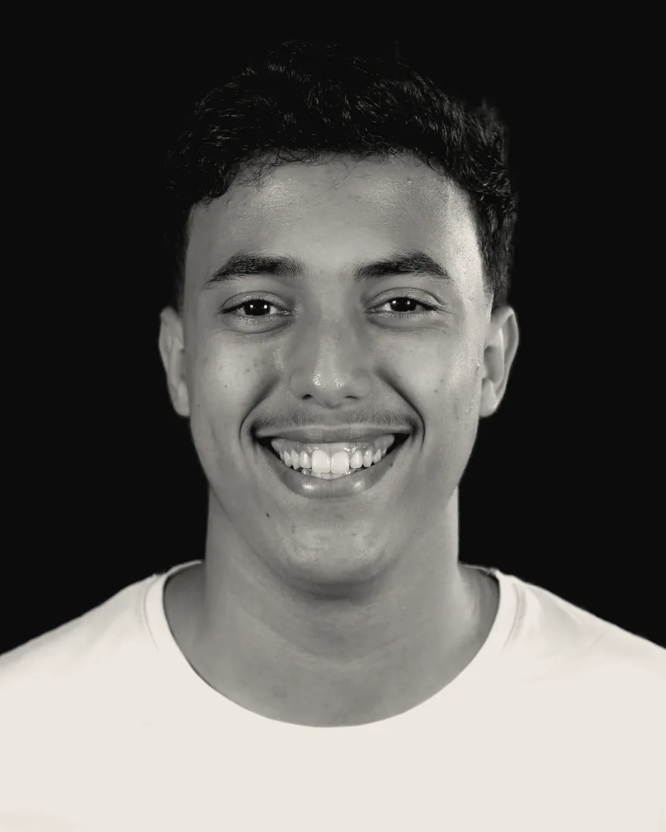 Portrait of Taha Koulal, smiling, in a white t-shirt